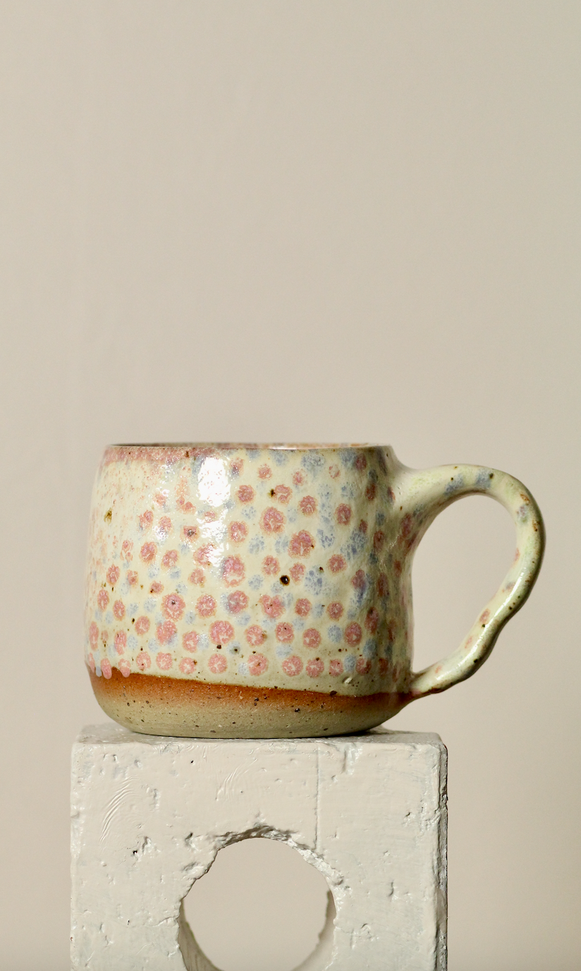 Ceramic mug with dot pattern on a beige background