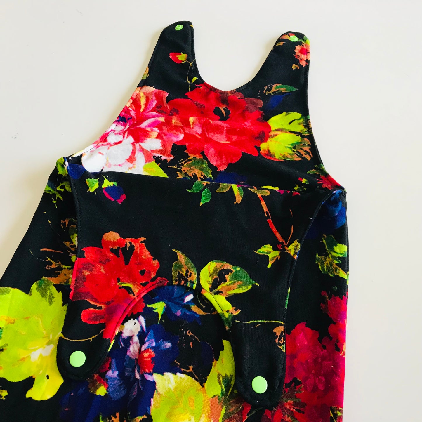 Colorful floral baby romper with black background on a white background