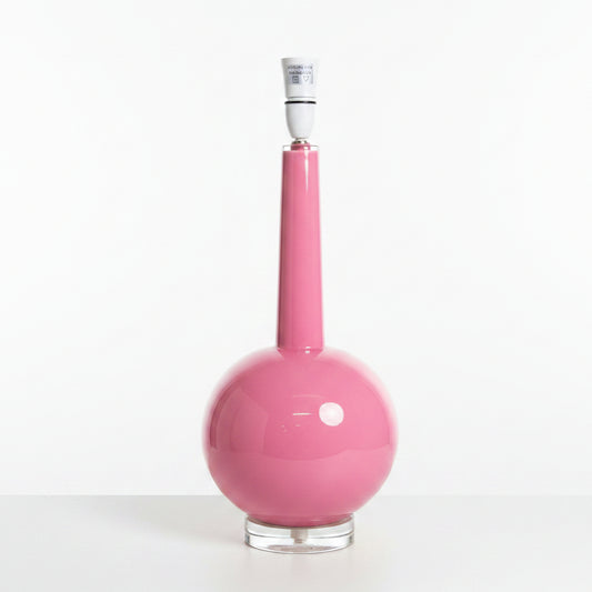 A modern pink table lamp with a glossy spherical base, a long narrow neck, and a clear glass or acrylic circular stand, shown on a white background.