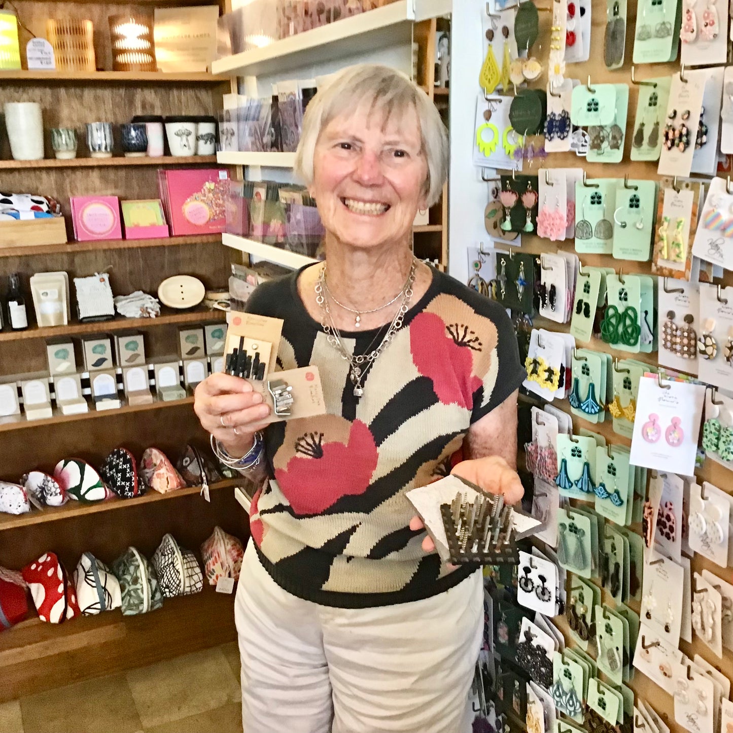 Woman holding small items in a store with shelves and displays in the background