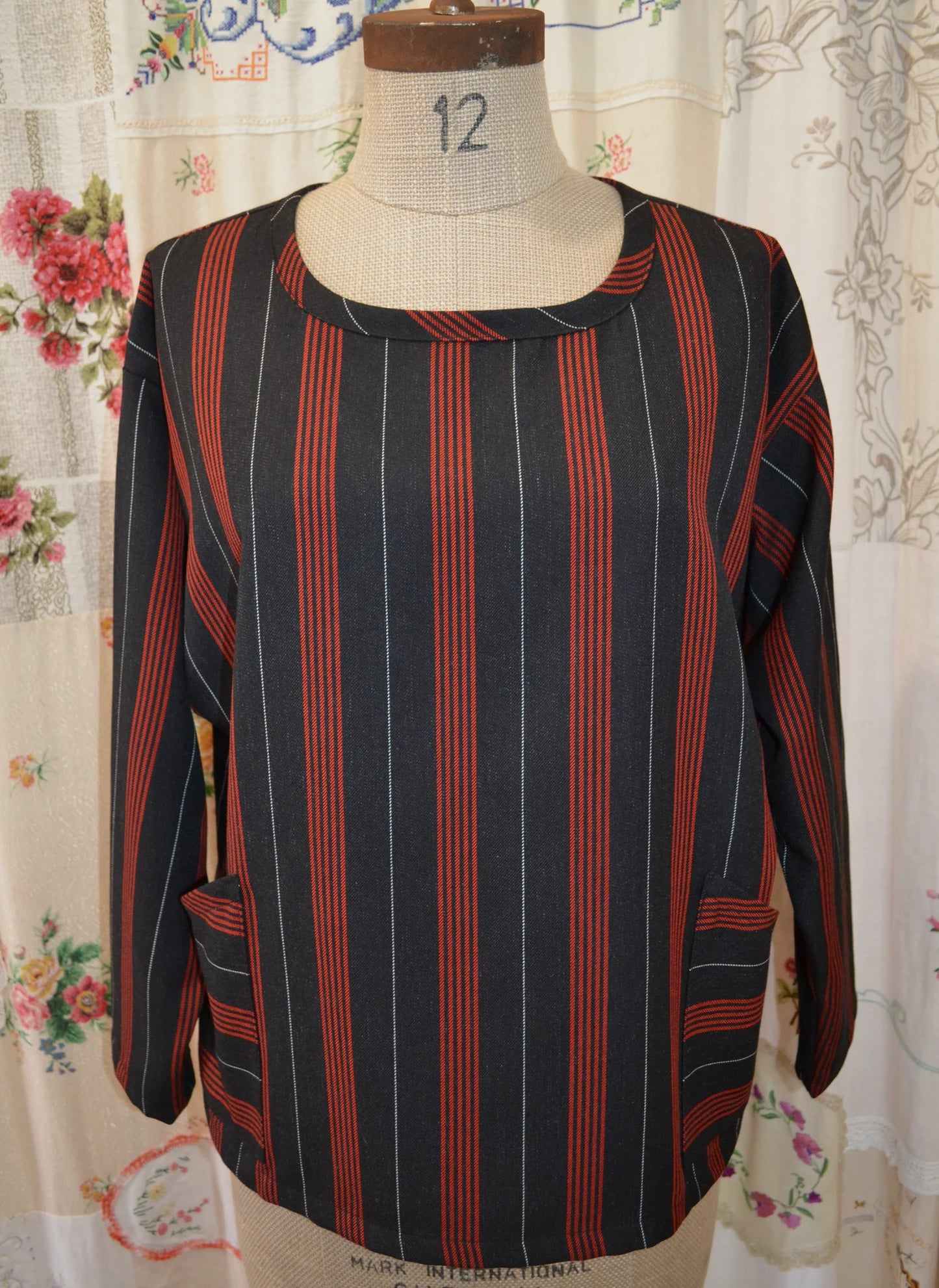 Striped long sleeved kite top on a mannequin against a floral curtain background