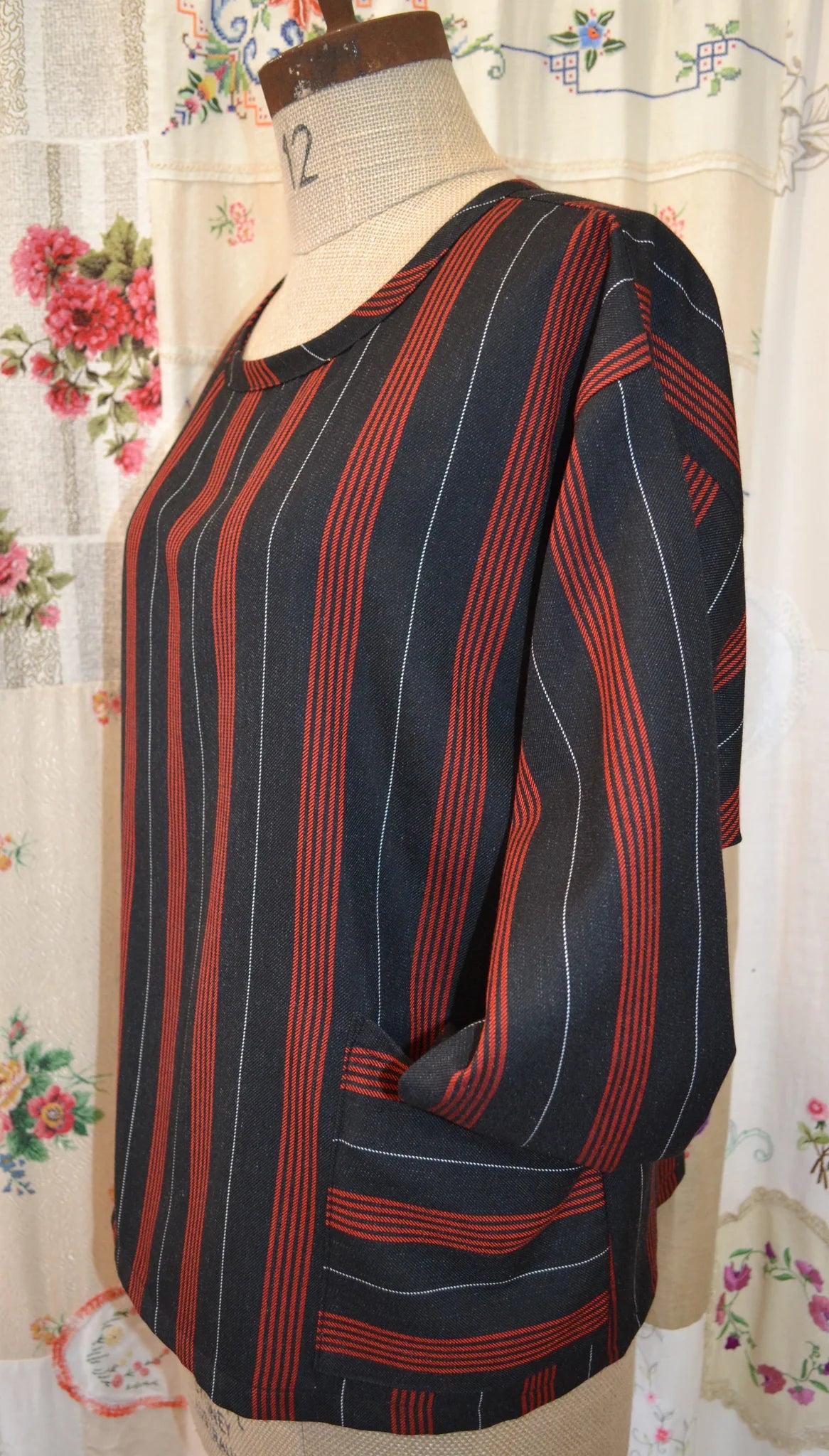 Striped long sleeved kite top on a mannequin against a floral curtain background