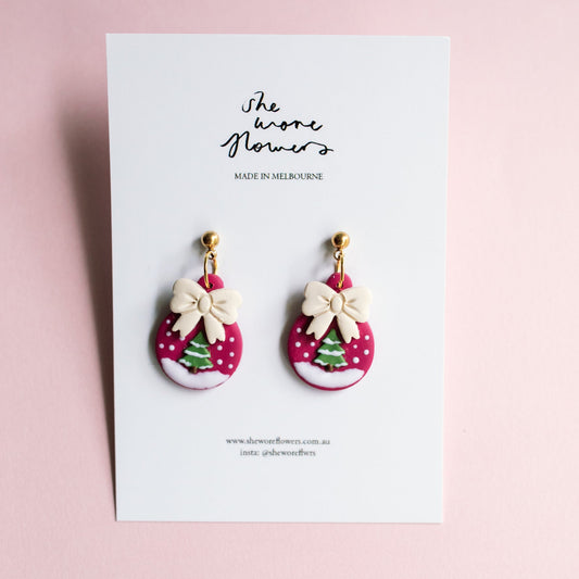Pair of earrings with pink and white polka dot design on a card with 'the wore flowers' branding.