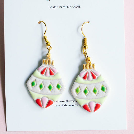 Pair of earrings on a card with 'the more flowers' branding on a pink background