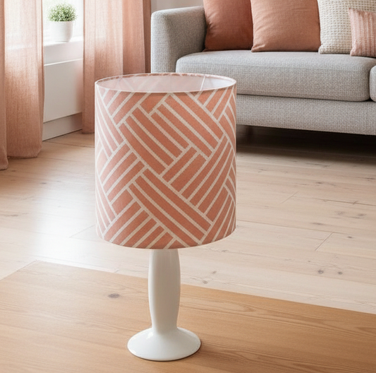 Lamp with a geometric patterned shade on a wooden floor in a living room.