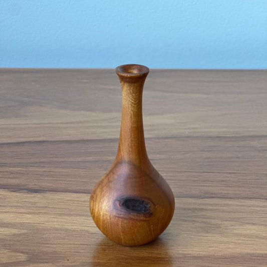 Wooden pepper grinder on a wooden surface with a light blue background
