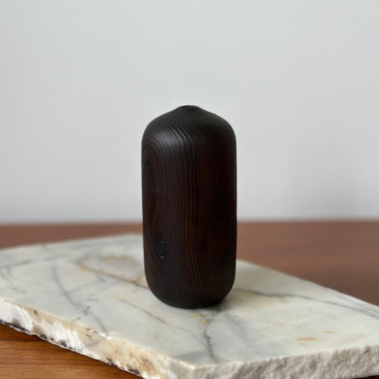 Black cylindrical object on a marble slab with a neutral background