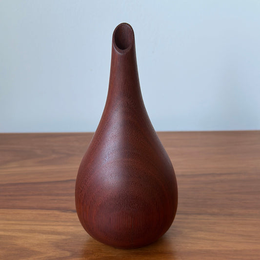 Wooden pear-shaped object on a wooden surface with a white background