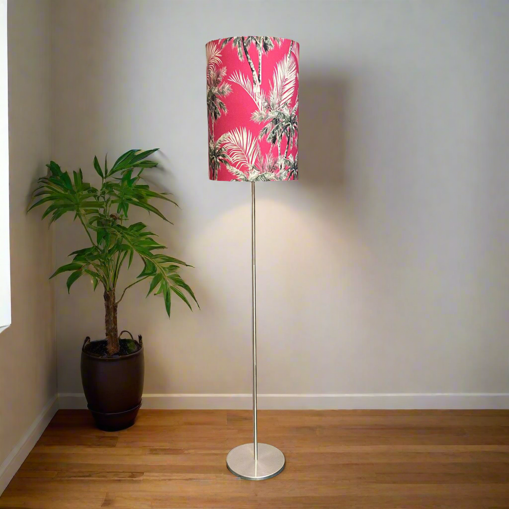 Floor lamp with a pink floral shade next to a potted plant in a room.