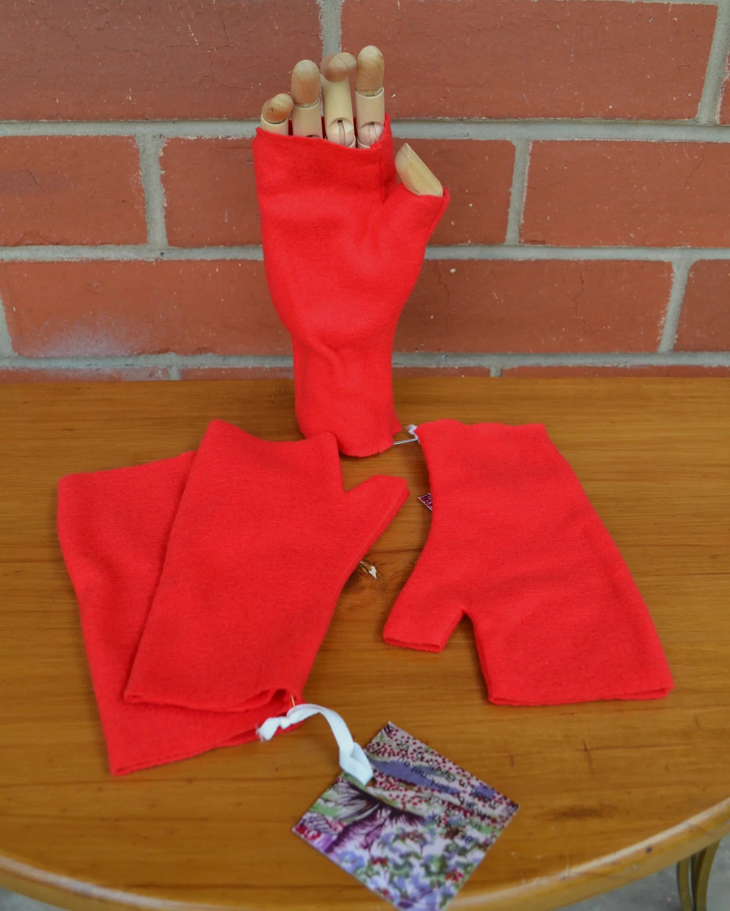 Red arm warmers on a wooden surface with a brick wall background