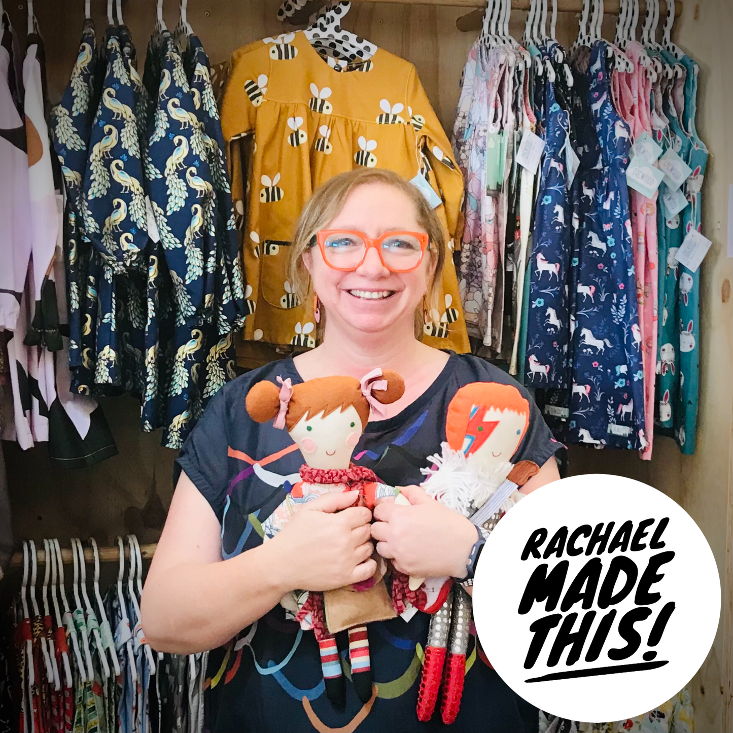 Co owner Rachael from Orcwood holding two of her handmade dolls, with a circle that reads Rachael Made This
