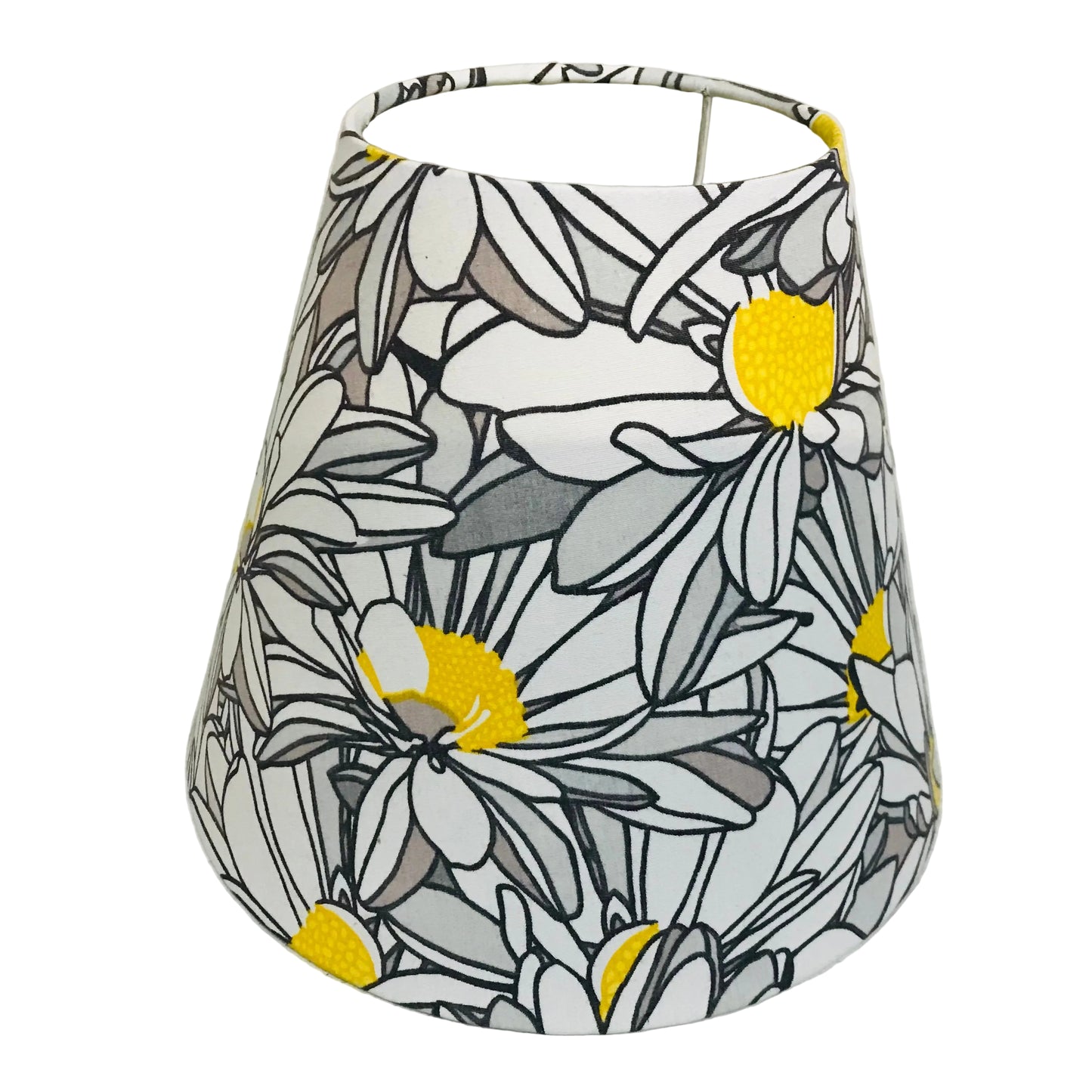 A fabric lampshade featuring a stylized daisy pattern in white, gray, black, and bright yellow, photographed against a plain off-white background.