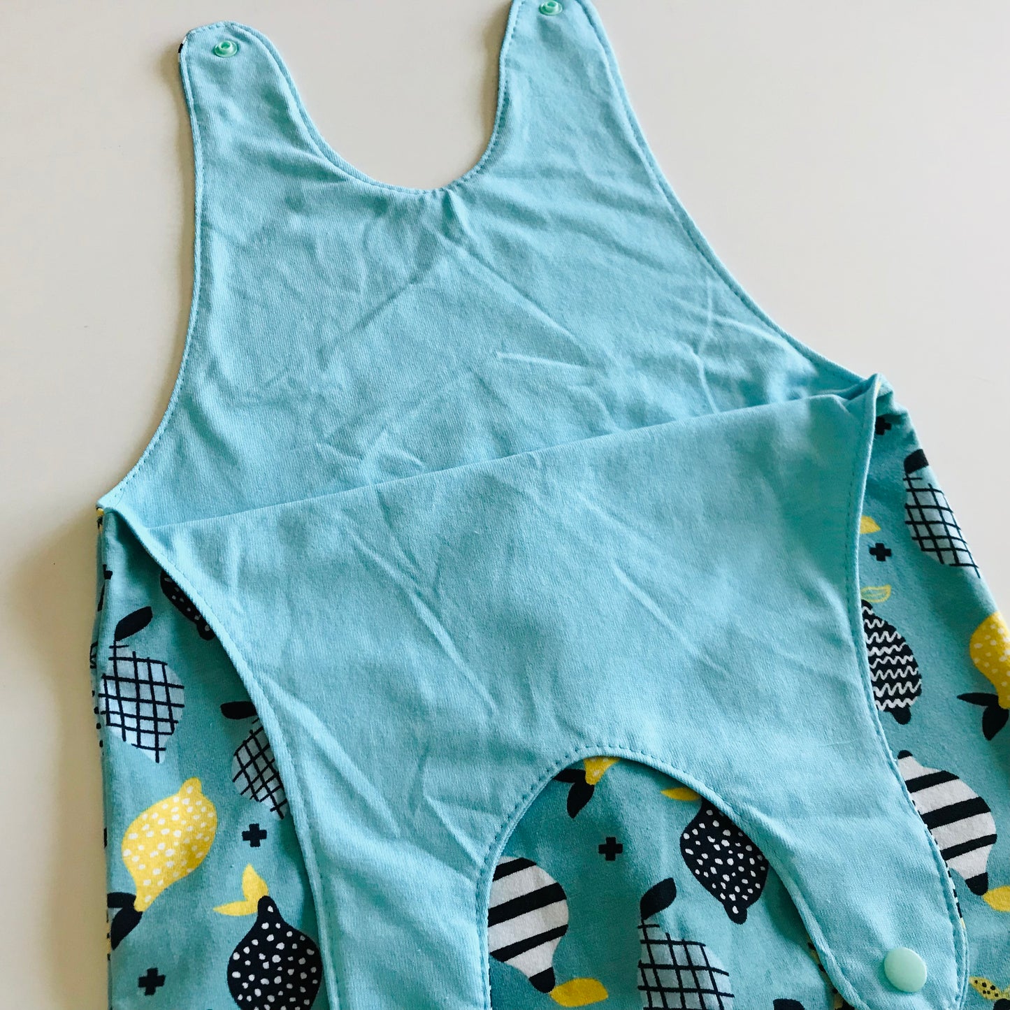 Light blue romper with lemon pattern on a beige background