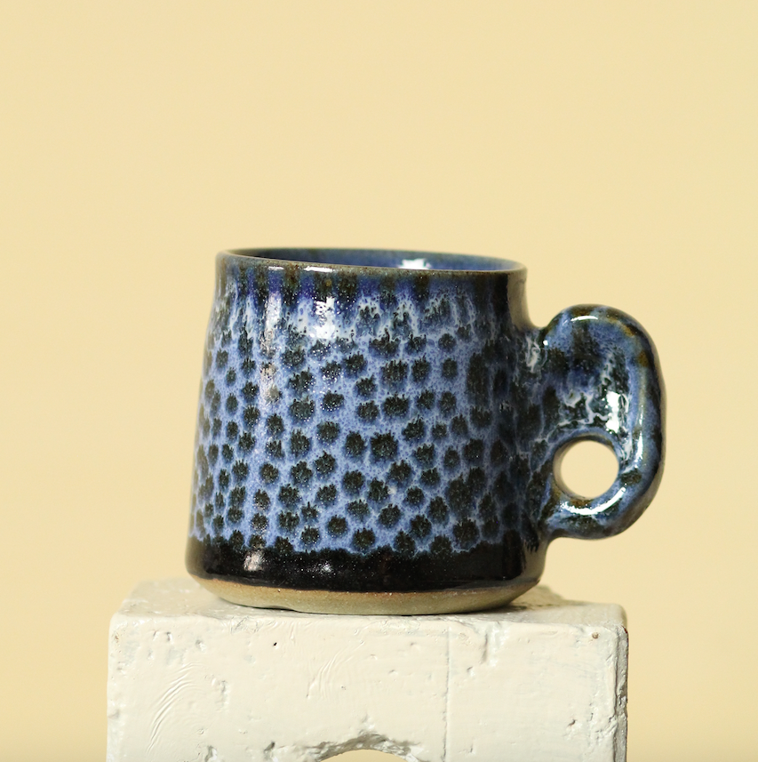 Blue ceramic mug with a textured pattern on a beige background