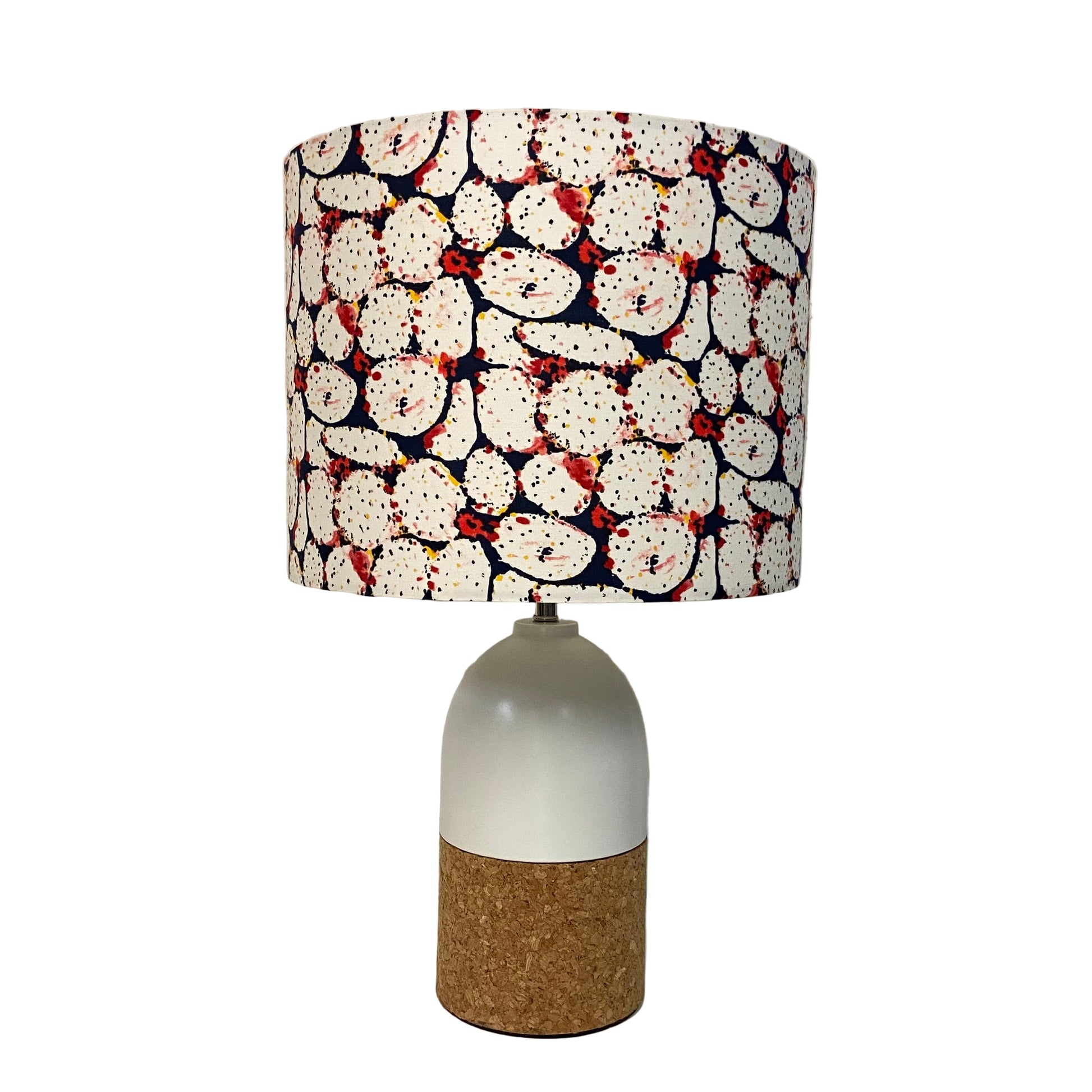 Lamp with a patterned shade and cork base on a white surface.