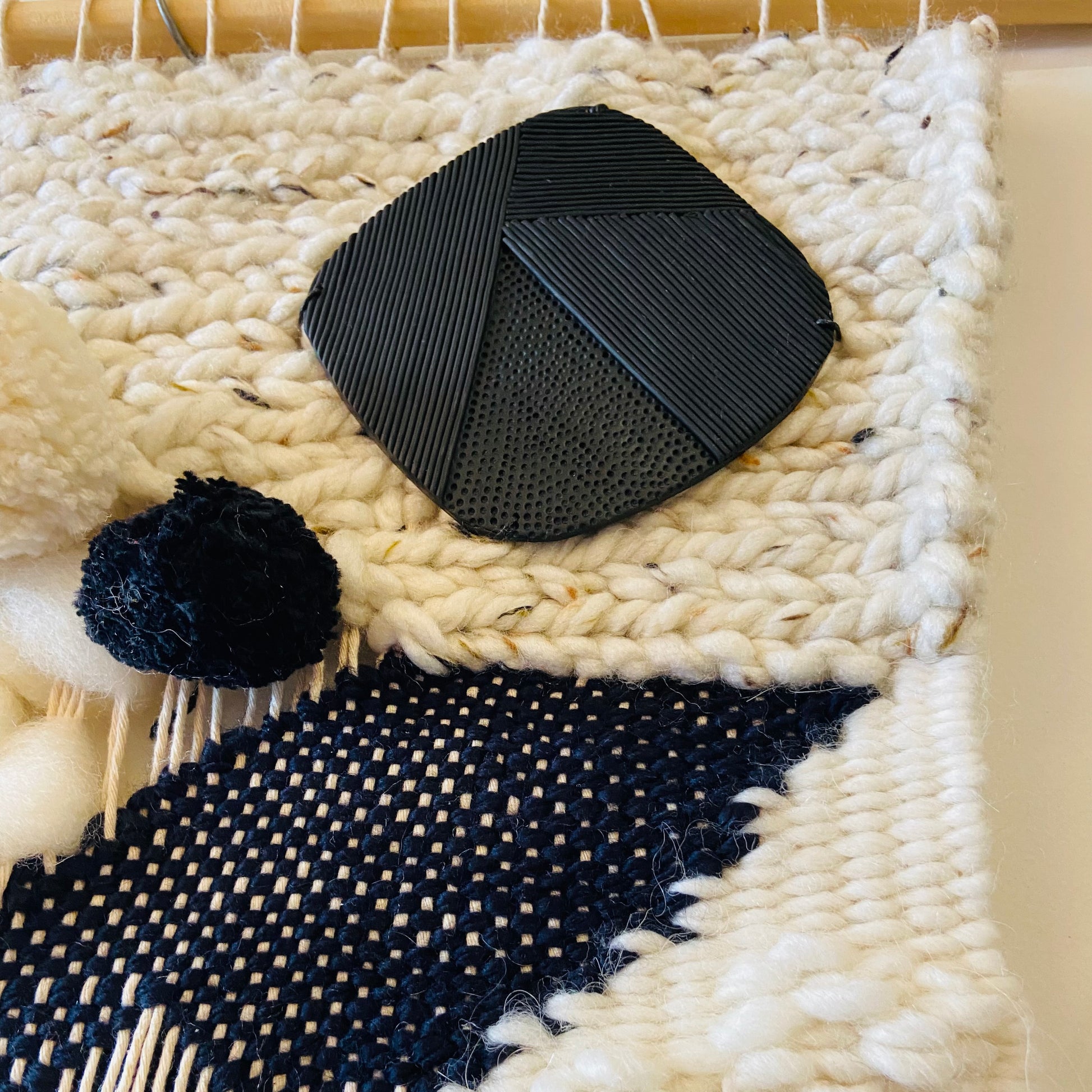 Black woven pouch on a textured white and black fabric background