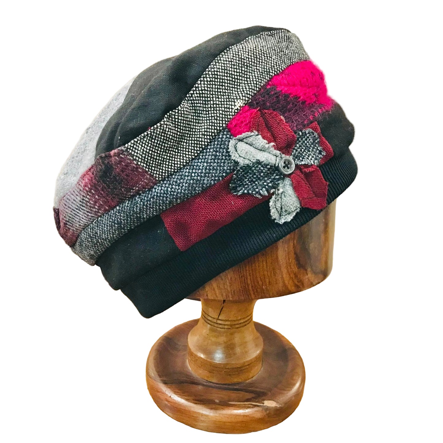 Decorative hat with plaid and floral patterns on a wooden mannequin head.