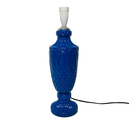 Blue textured table lamp on a white surface with a white background
