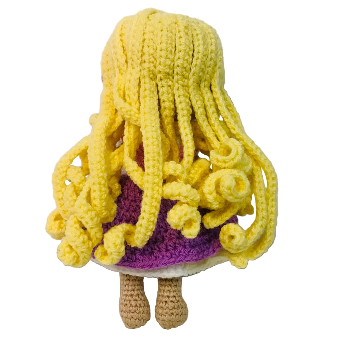 Crocheted doll with yellow hair and purple outfit on a white background