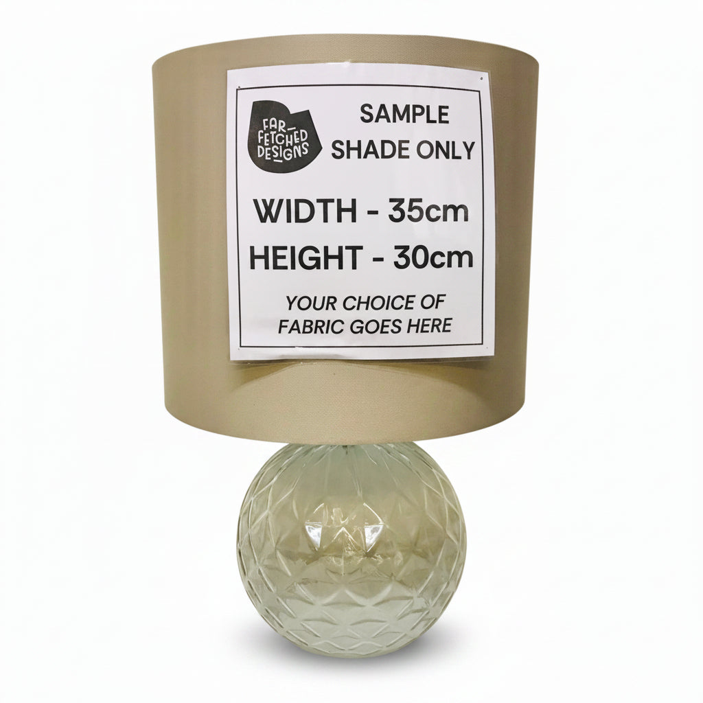 Lamp with a beige shade and glass base on a white background