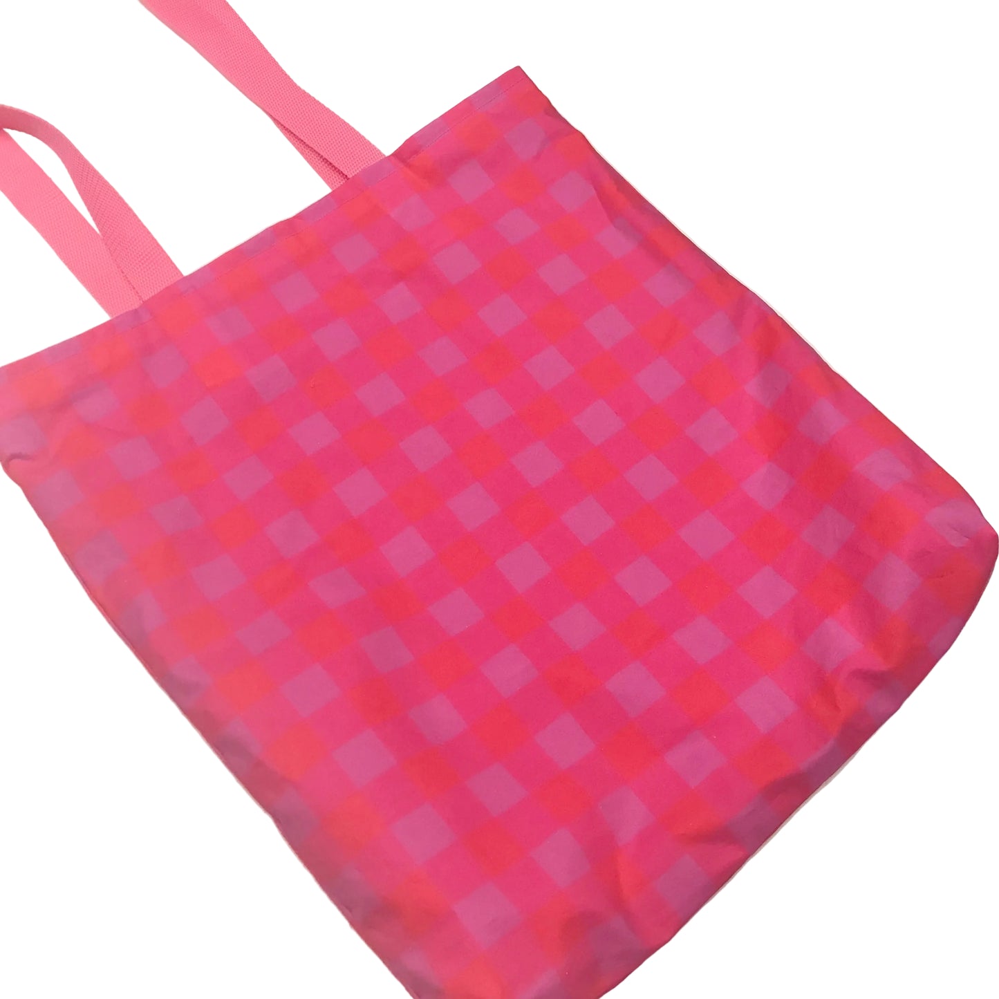 A pink and magenta checkered reusable tote bag with two shoulder straps, shown on a plain off-white background.