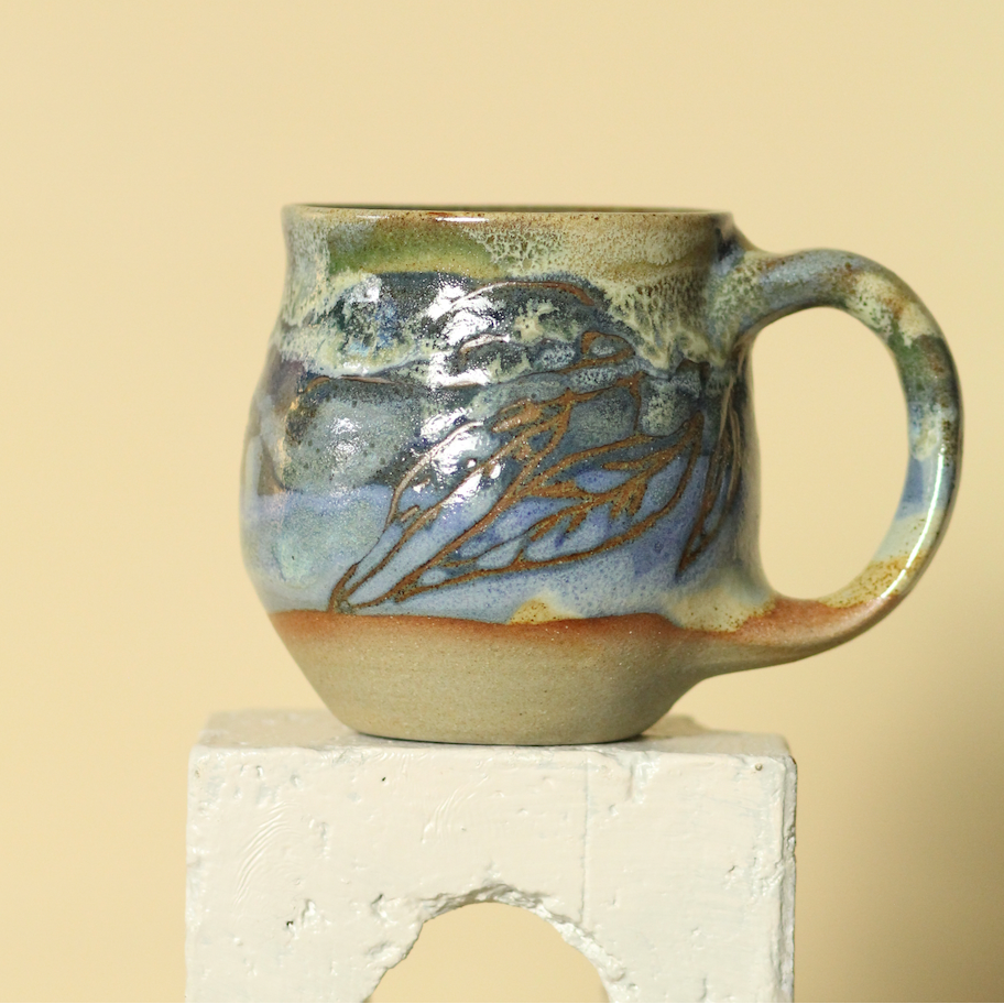 Ceramic mug with decorative handle on a beige background