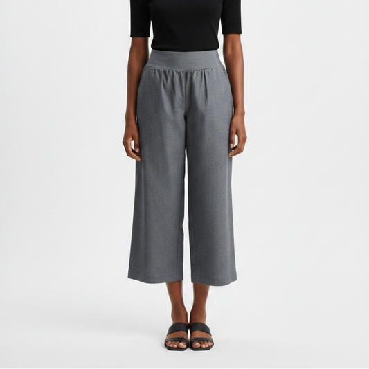Woman wearing a black top and gray wide-leg pants on a white background