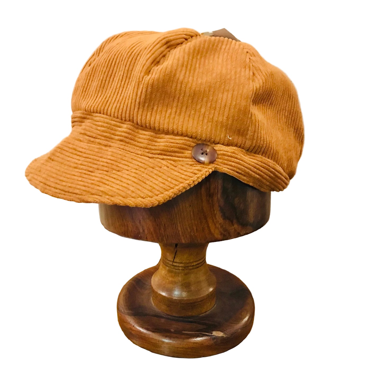 Brown corduroy cap on a wooden mannequin head with a beige background