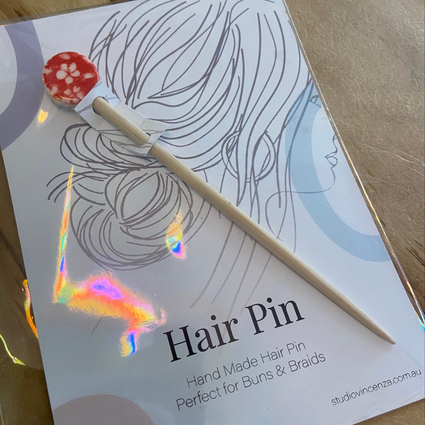 Hair pin with packaging featuring a woman's hair and text on a wooden surface