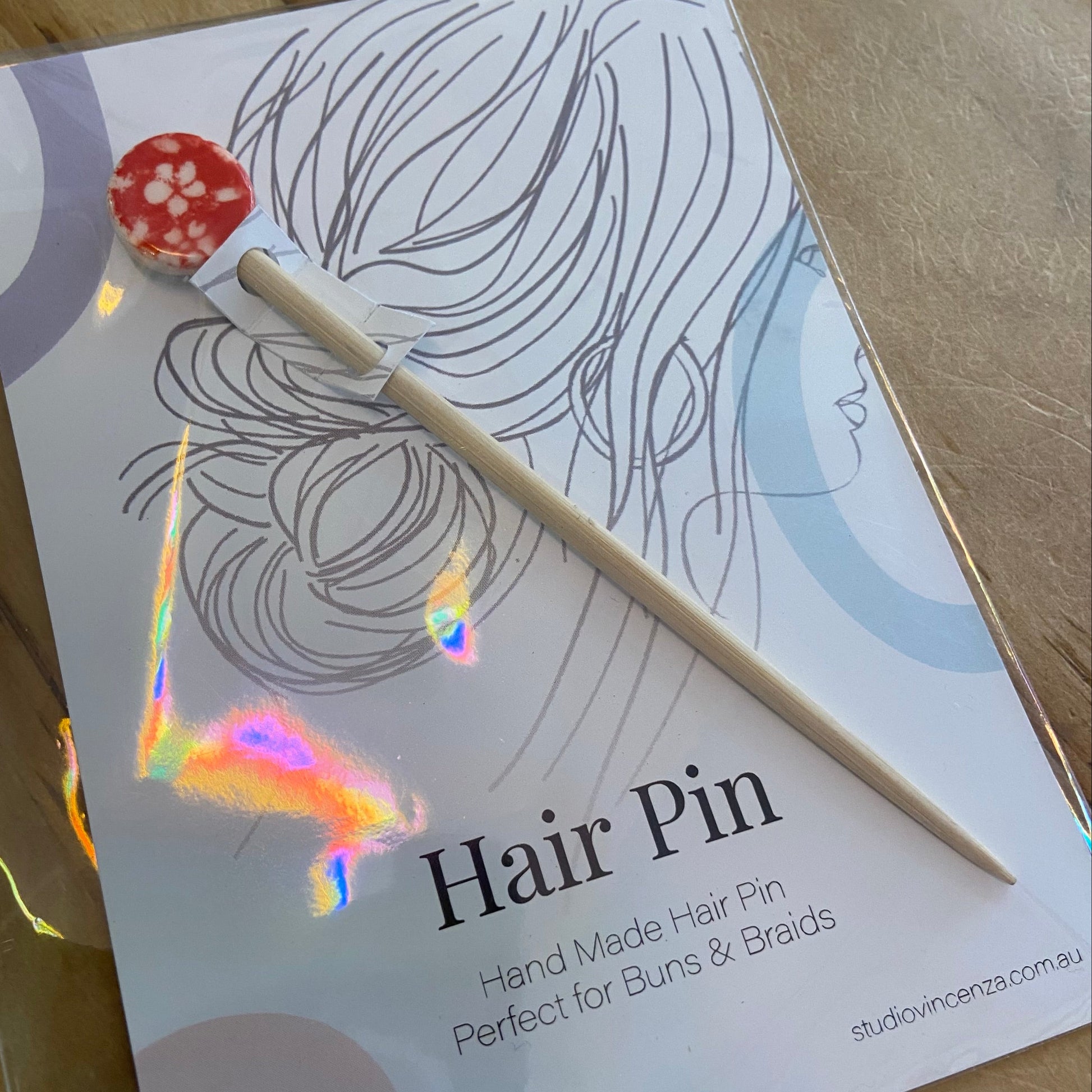 Hair pin with packaging featuring a woman's hair and text on a wooden surface