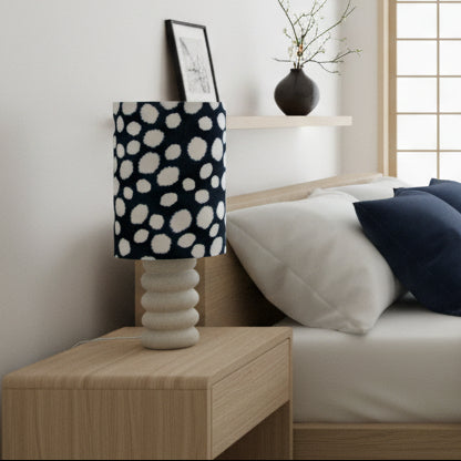 Lamp with a navy and white polka dot shade on a white base 
