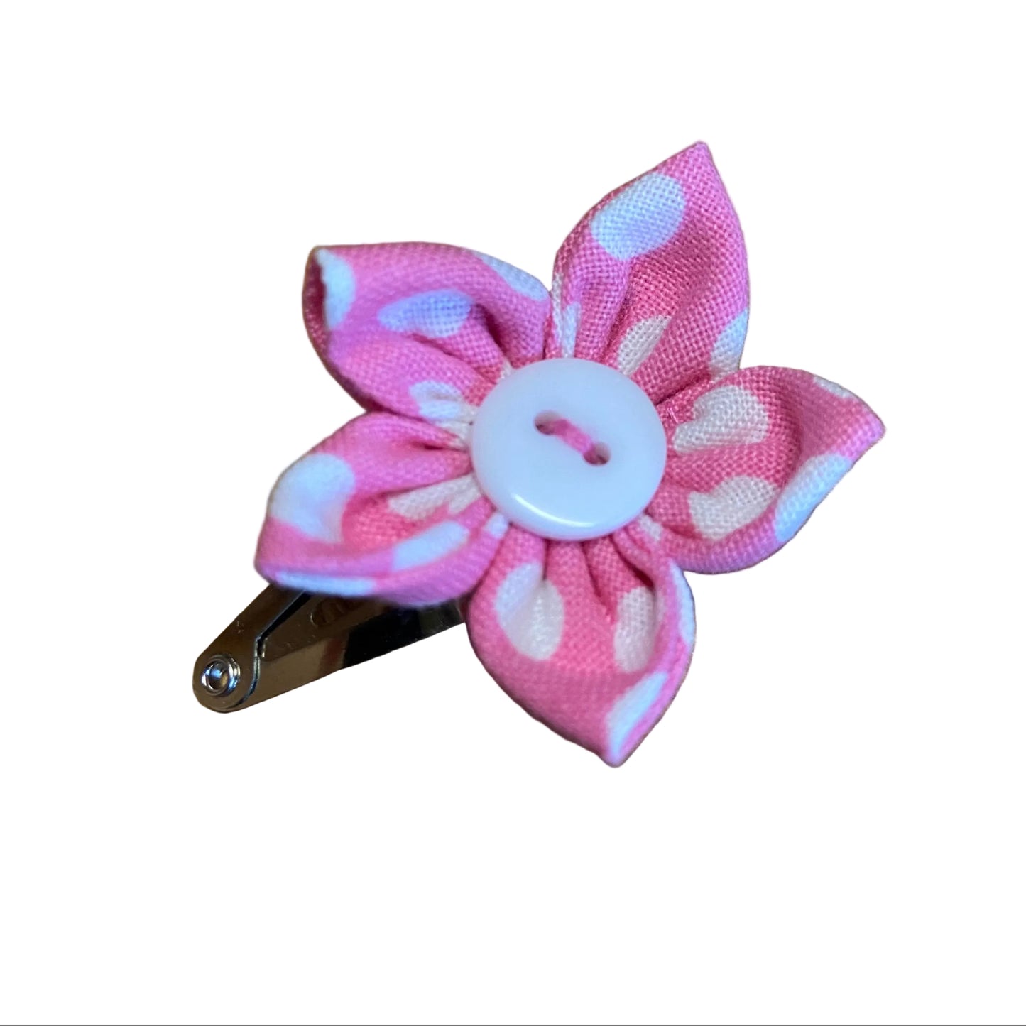 Pink and white floral hair clip with a button on a wooden surface