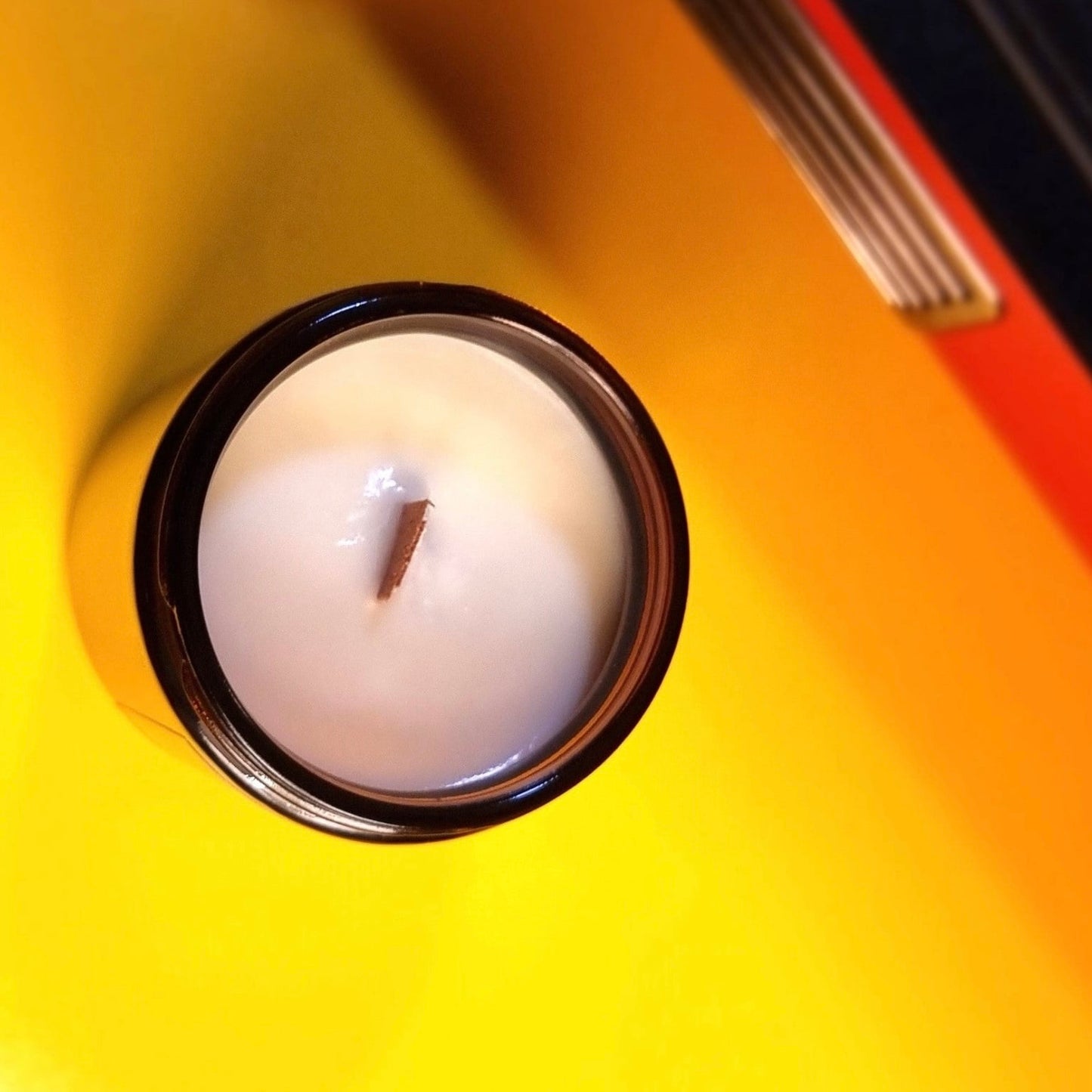 White candle in a black holder on a yellow surface
