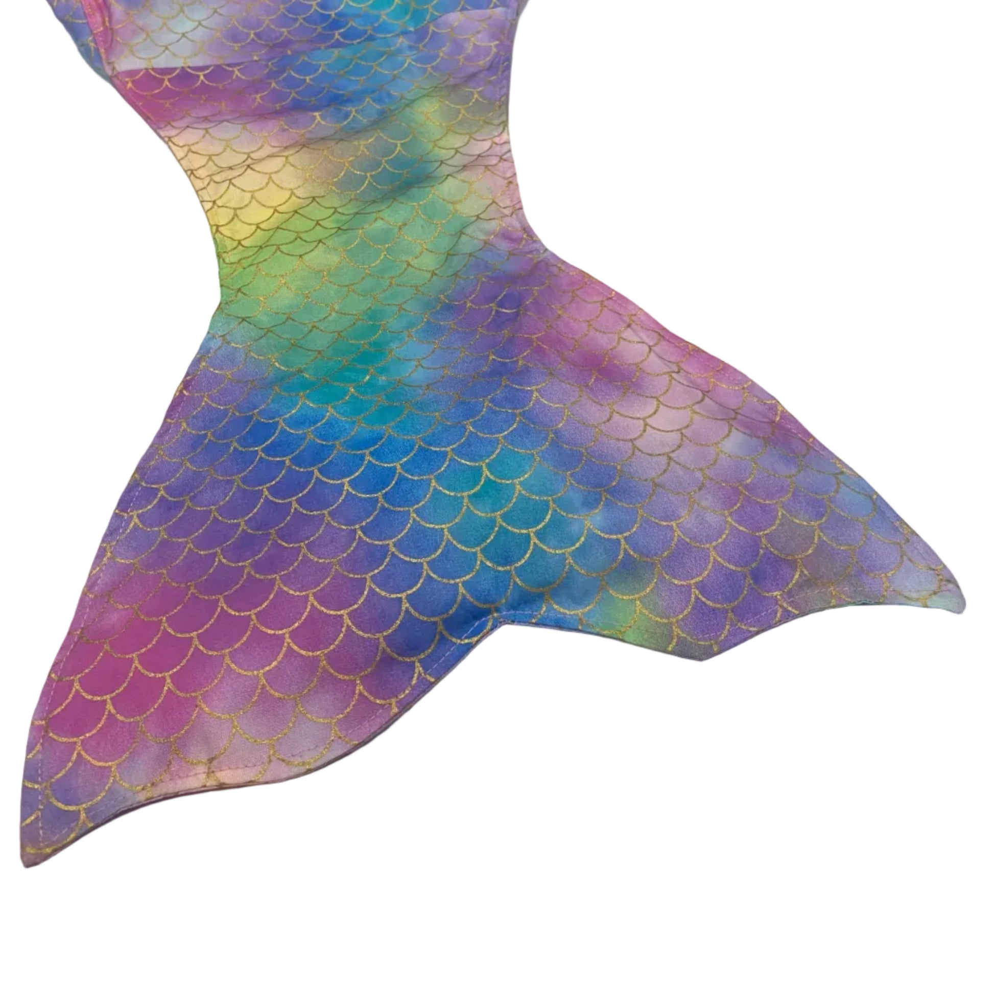 Colorful mermaid tail fin on a white surface with a bookshelf in the background