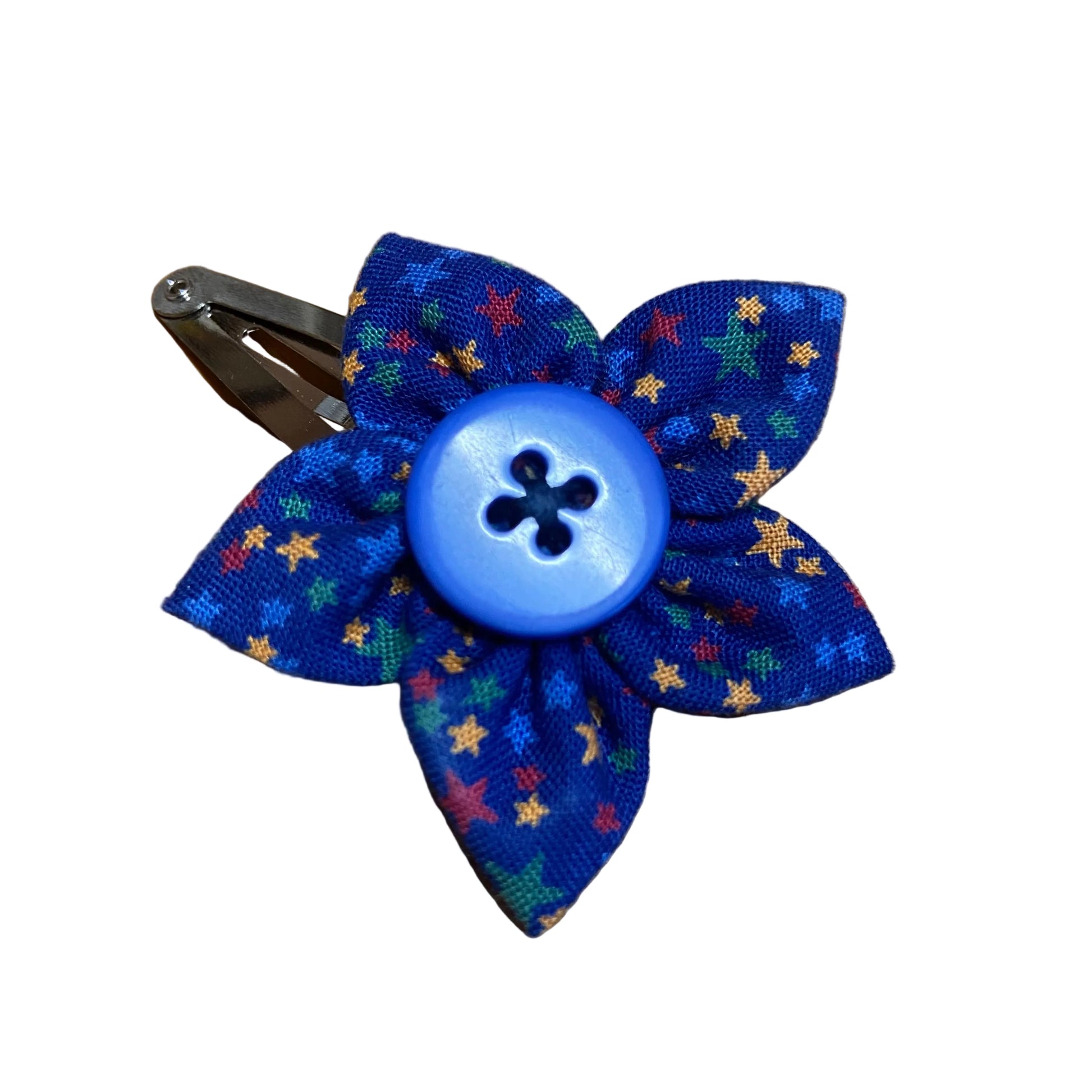 Blue fabric flower hair clip with a button center on a wooden surface