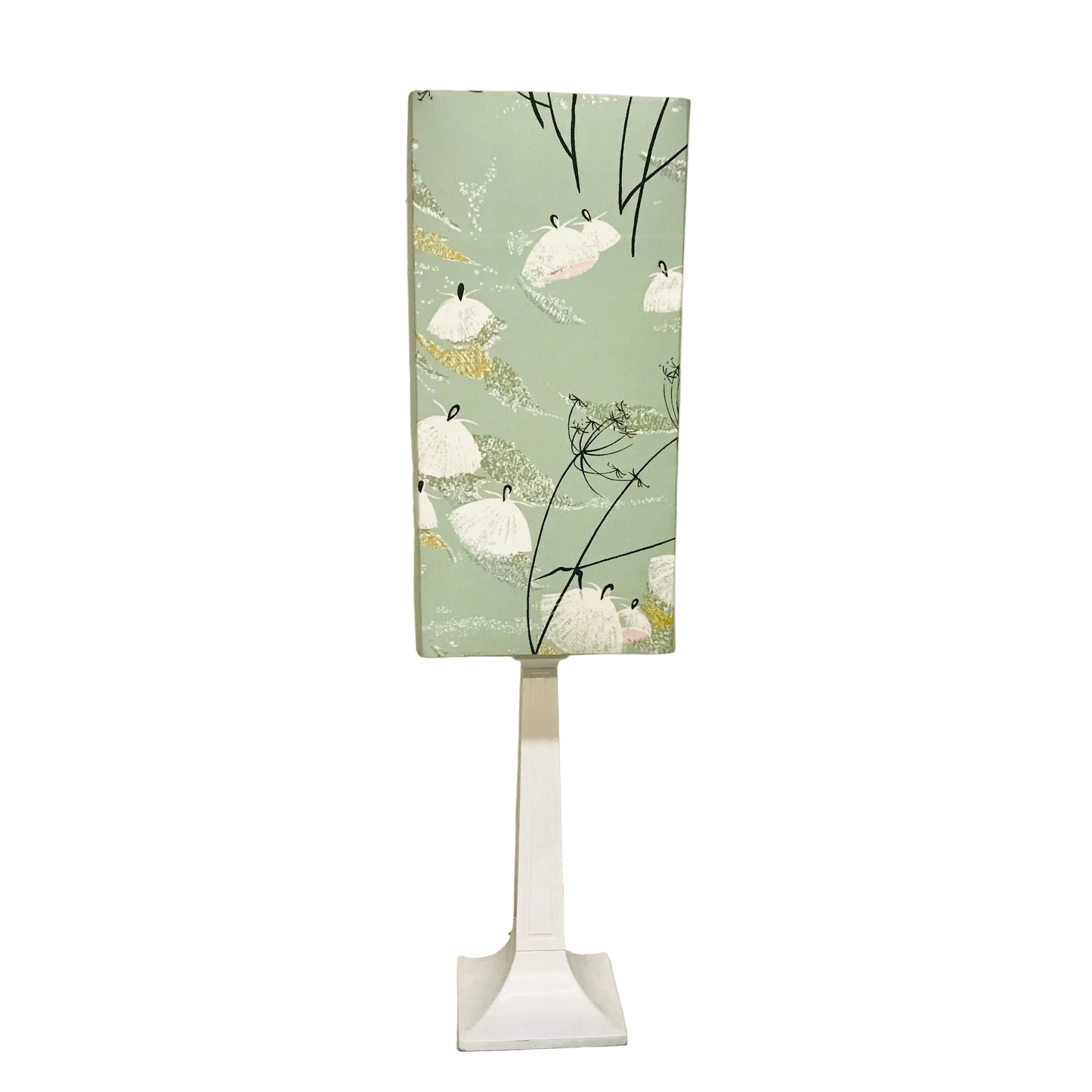 A modern table lamp with a rectangular light box featuring a sage green background and a pattern of white swans and black branches, mounted on a sleek white pedestal stand.