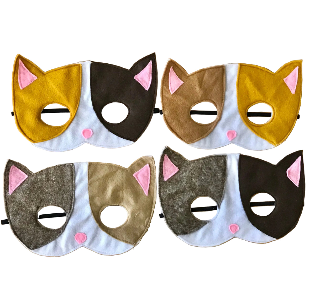 Four felt cat face masks arranged in a 2x2 grid on a light wood background. The masks feature different cat color patterns: yellow and brown, brown and white, gray and tan, and gray and brown, each with pink inner ears and pink nose details.