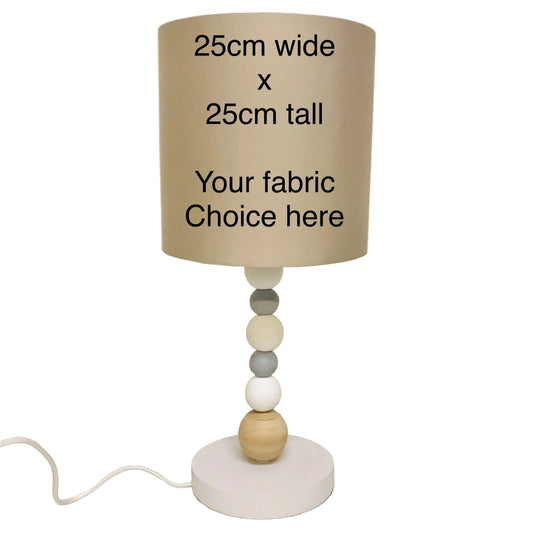 Lamp with wooden base and beige fabric shade on a plain background