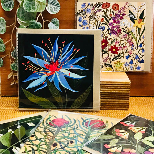 Collection of floral greeting cards on a surface with plants in the background