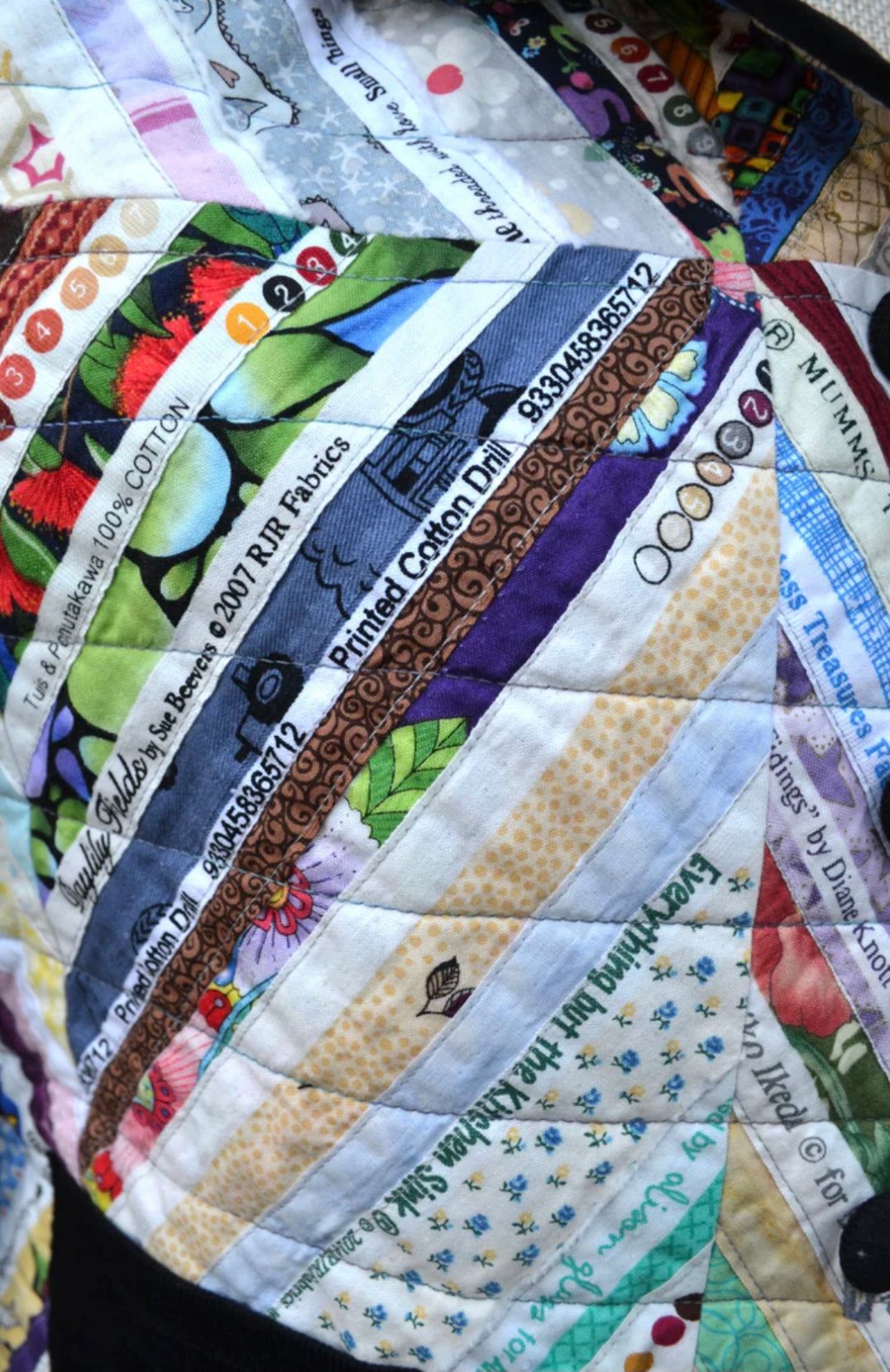 Close-up of a patchwork quilt with visible fabric labels.