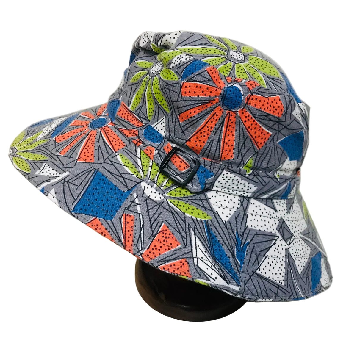 A wide-brim sun hat with a colorful geometric and floral print on a gray base, displayed on a black stand against a plain white background.