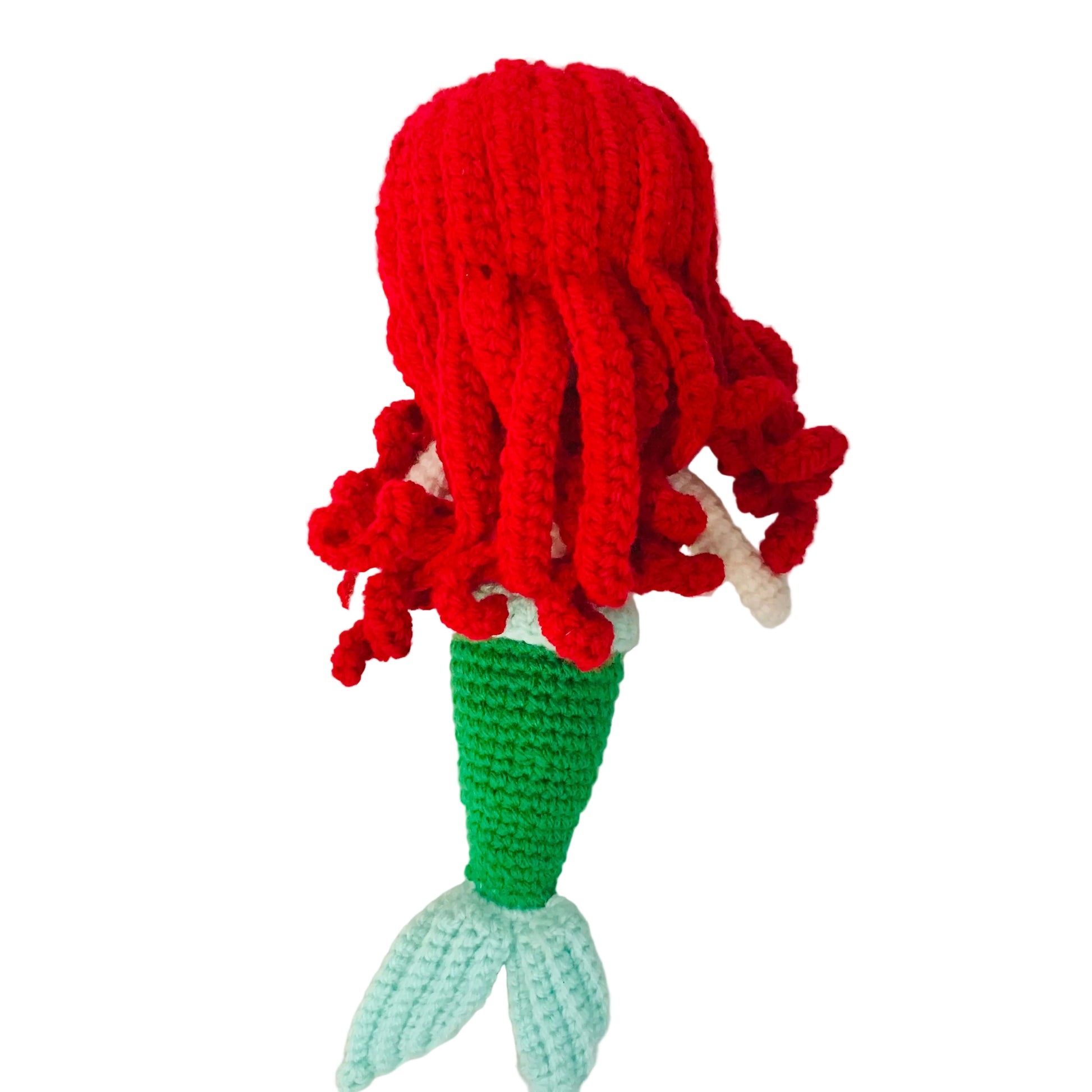 Crocheted mermaid toy with red hair and a green tail on a white background