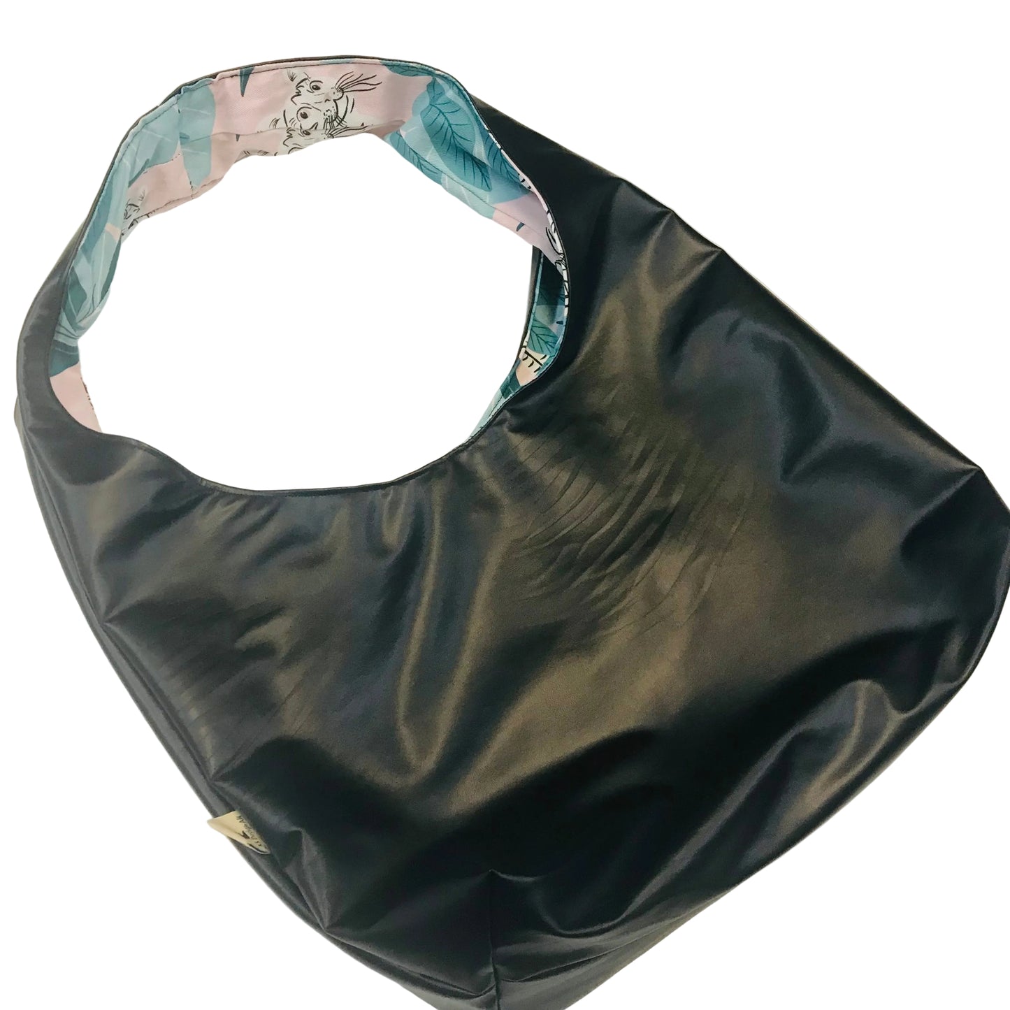 A black faux-leather hobo shoulder bag with a colorful patterned lining visible inside the strap, photographed on a plain off-white background.