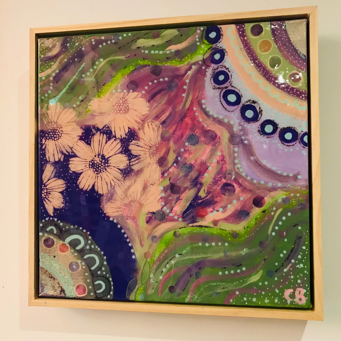 Framed abstract artwork with floral elements on a beige wall