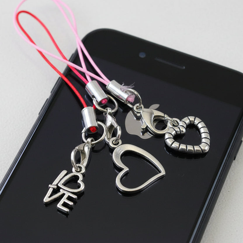 Phone charm with heart and 'I âŇVE' charms on a smartphone