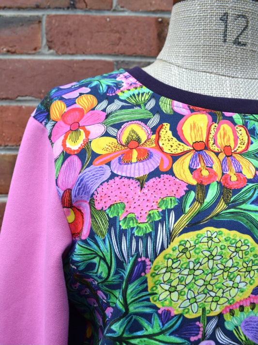 Colorful floral pattern on a garment against a brick wall.