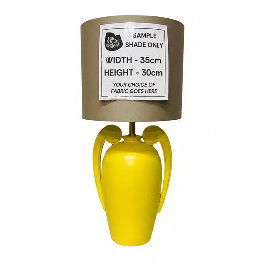 Yellow lamp with a gray shade on a white surface, featuring a label.