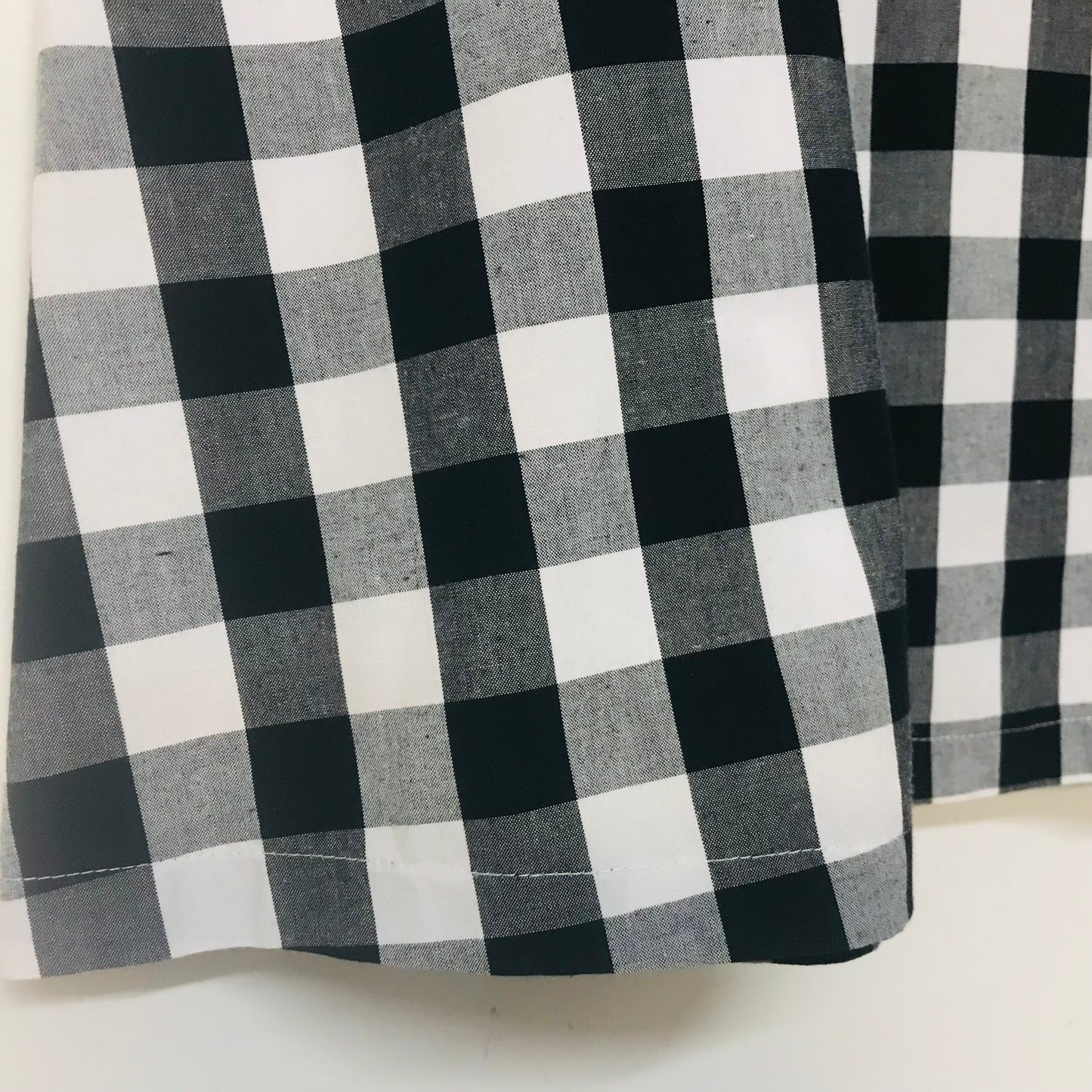 Black and white buffalo check plaid fabric shown in a close-up, highlighting the woven texture and pattern.