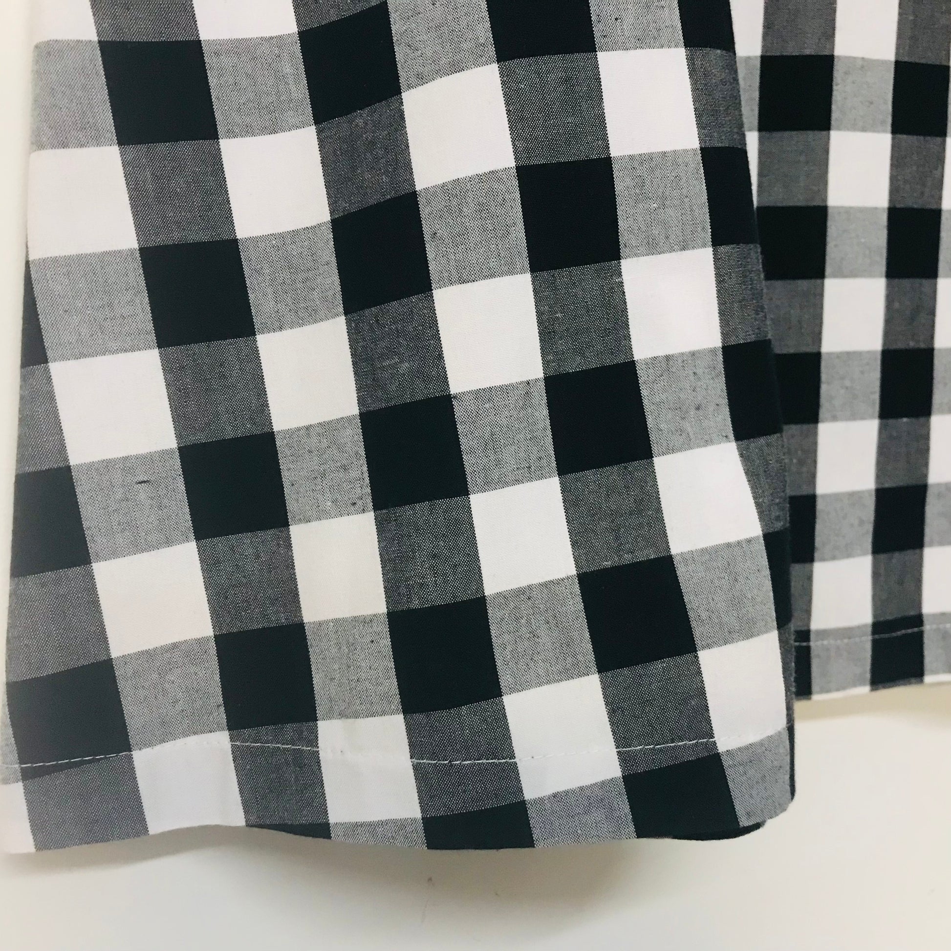 Black and white buffalo check plaid fabric shown in a close-up, highlighting the woven texture and pattern.