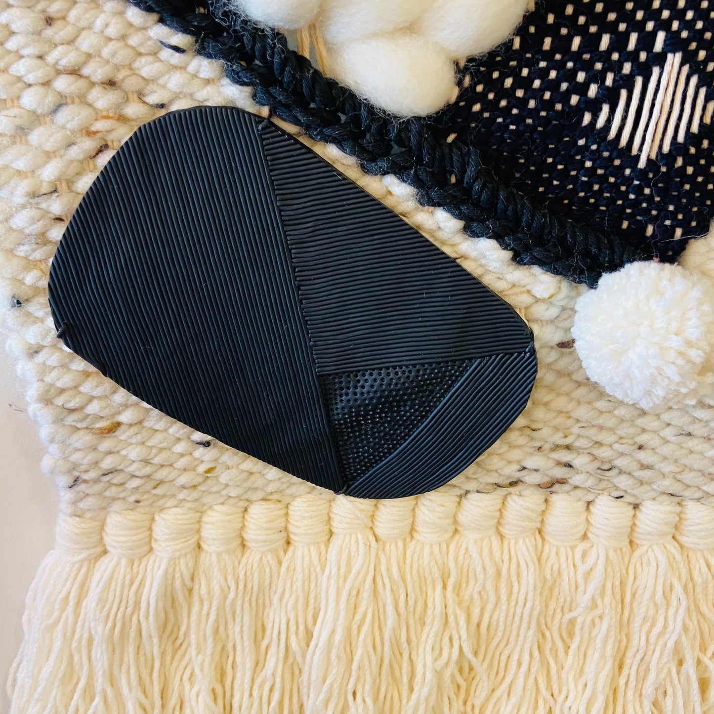 Black textured object on a woven mat with white yarn